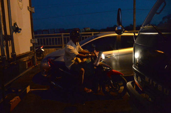 A vendor rides his motorcycle in the middle of the congested bridge. Photo: Tuoi Tre
