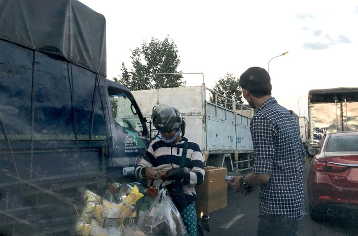 A truck driver buys snacks from a vendor. Photo: Tuoi Tre