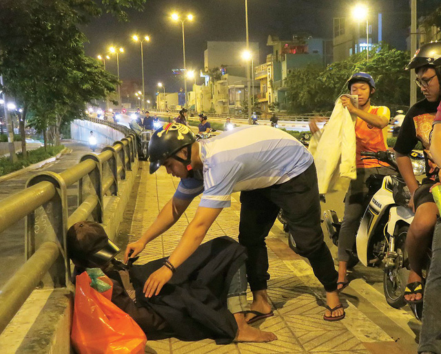 Members of a charity group gives warm blanket to a homeless man sleeping on a bridge in Ho Chi Minh City. Photo: Tuoi Tre