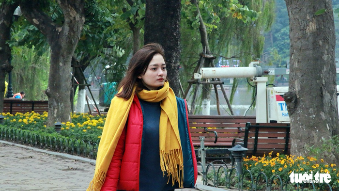 A woman wears jackets and woolen scarves amidst the cold air.