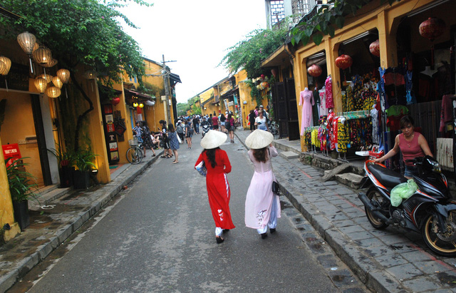 Two women wearing the 'ao dai' (Vietnam's traditional long gown) walks in an old quarter of Hoi An. Photo: Tuoi Tre