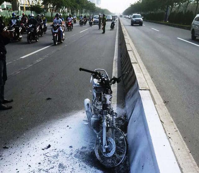 Although extinguished by a local, the flames burnt the whole vehicle down to its metal frame, leaving it stranded beside the median barrier of the Hanoi Highway. Photo: Tuoi Tre