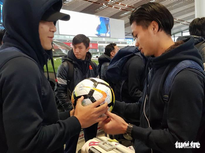 Striker Nguyen Cong Phuong (R) signs a ball at the airport in Changzhou. Photo: Tuoi Tre