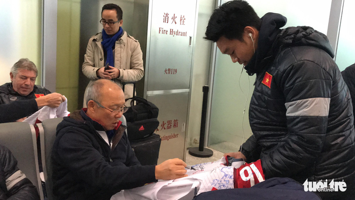 Head coach Park Hang-seo signs T-shirts for fans at the airport. Photo: Tuoi Tre