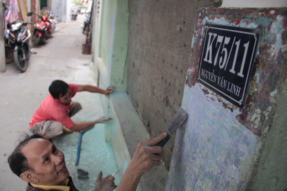 Local men residing along the alley clean a wall in preparation for frescos. Photo: Tuoi Tre