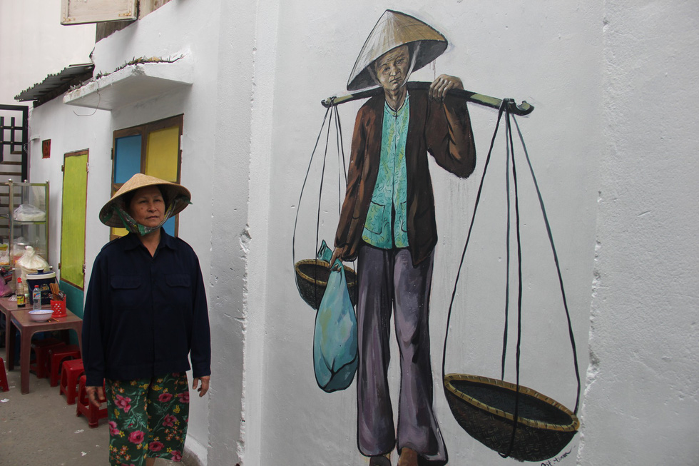 A fresco of a vendor carrying baskets hung from a pole over her shoulder. Photo: Tuoi Tre