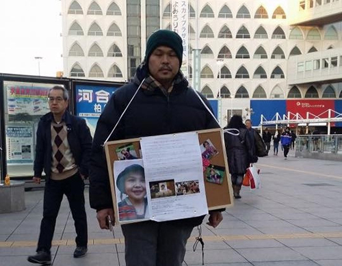 Le Anh Hao, father of Le Thi Nhat Linh, carries a sign on a street in Japan calling for signatures to pressure the court into handing down the death penalty for the culprit in his daughter’s murder in this photo posted by his wife on Facebook.