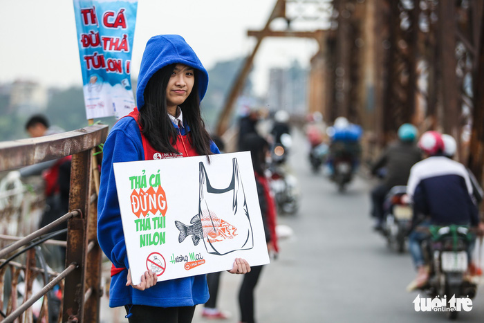 A member of the Ca Chep (Carp) volunteer group holds a sign saying “Release carp, not plastic bags” on Long Bien Bridge.