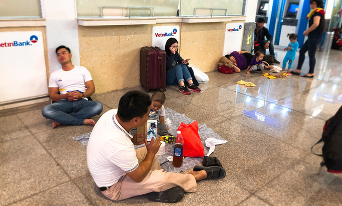 Passengers sit on the floor as they wait for their flights. Photo: Tuoi Tre