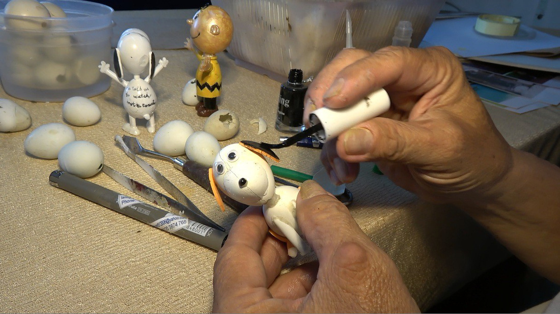 Tam adds paint to a dog statuette.