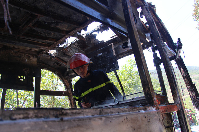 A firefighter inspects the inside of the passenger bus that had burnt down completely. Photo: Tuoi Tre