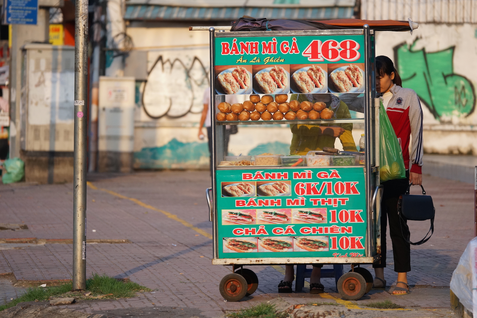 A woman buys banh mi (Vietnamese sandwich) from a street vendor on Phan Dang Luu Street, Ho Chi Minh City, on February 3, 2018. Photo: Tien Bui