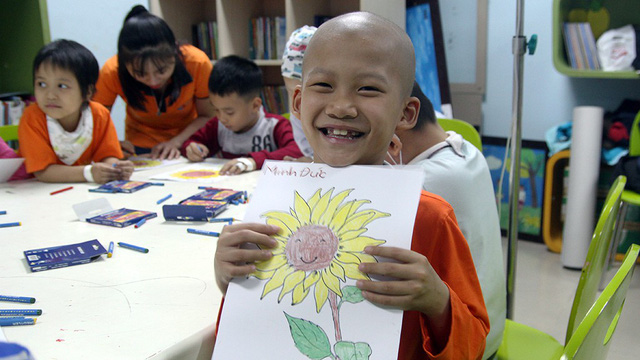 A leukimia patient, who has lost his hair due to chemotherapy, smiles as he shows his painting during a cancer awareness event at the National Institute of Hematology and Blood Transfusion in Hanoi, November 21, 2017. Photo: Tuoi Tre
