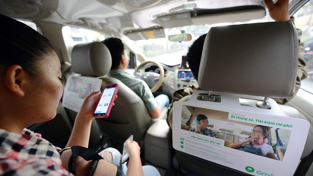 A woman looks at her smartphone aboard a Grab car in Ho Chi Minh City. Photo: Tuoi Tre