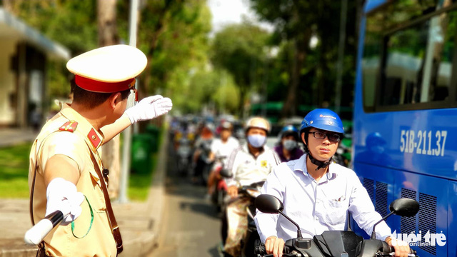 A traffic police officer controls traffic in front of the Reunification Palace.