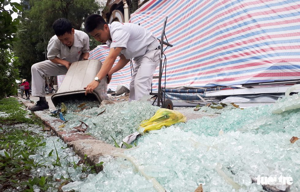 Two men collect shattered window glass after the blast. Photo: Tuoi Tre