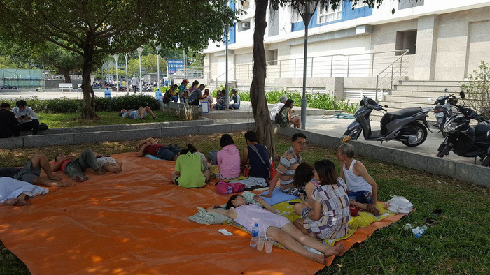Affected victims take a rest on the building campus after the fire. Photo: Tuoi Tre