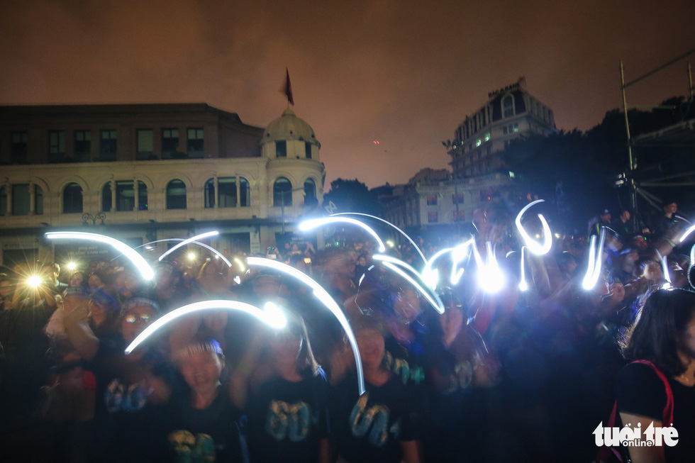Young people turn on their smartphone flashlights.