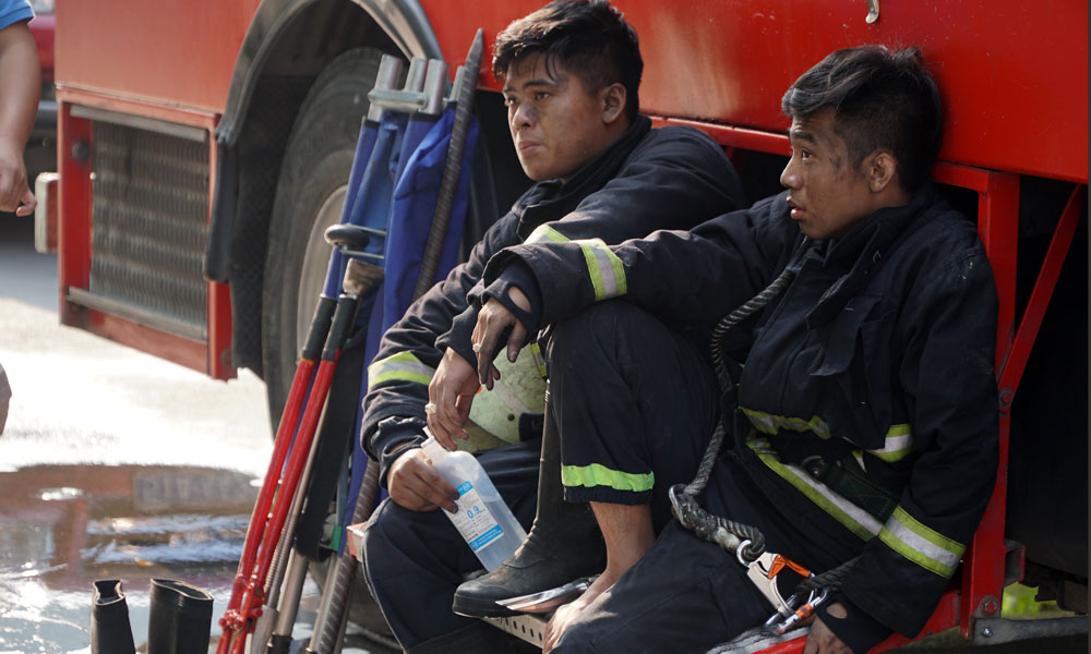 Two firefighters take a rest after the fire is put out. Photo: Vietnamnet