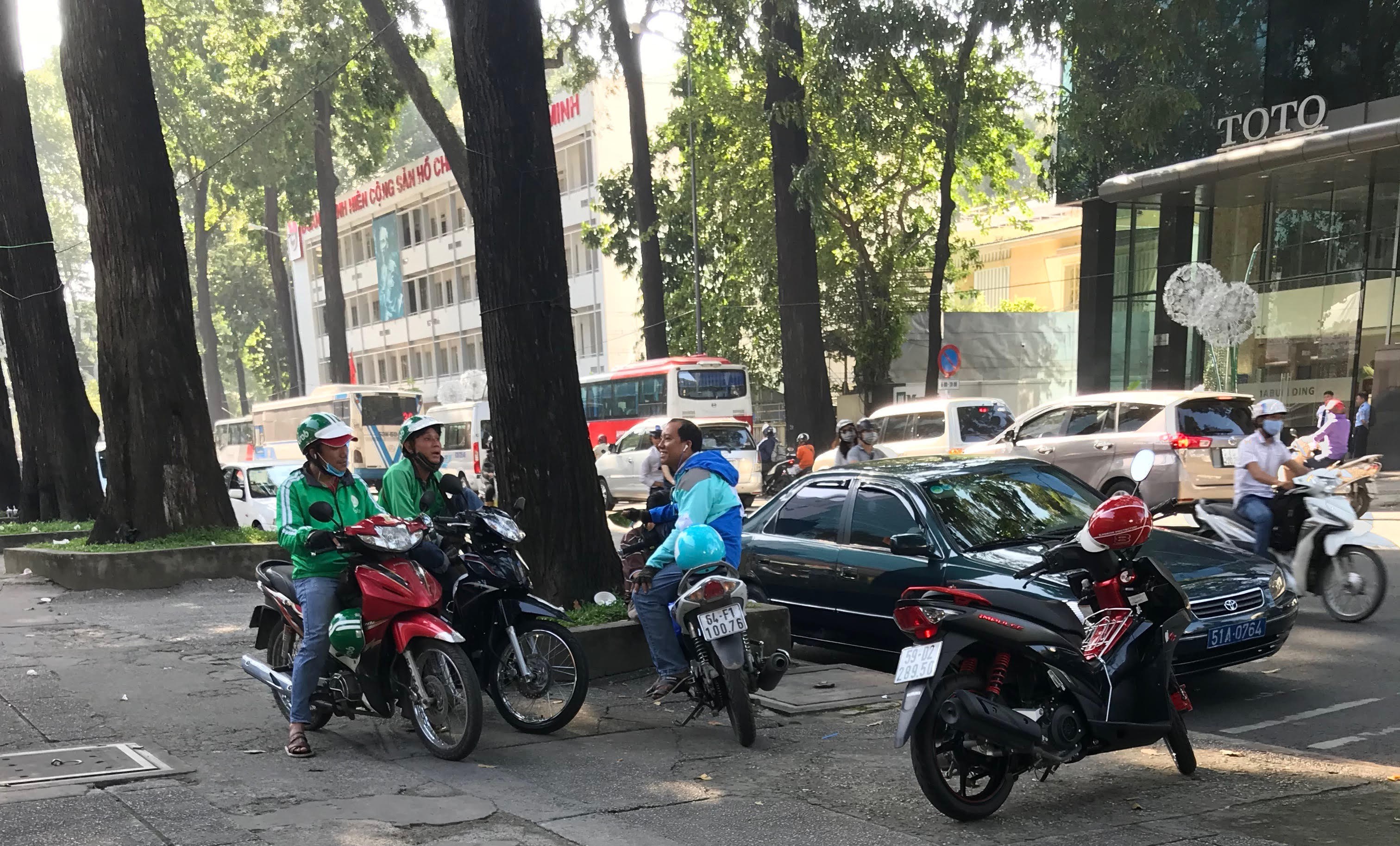 Two Grab drivers talk to a Uber driver in Ho Chi Minh City on December 17, 2017. Photo: Tuoi Tre