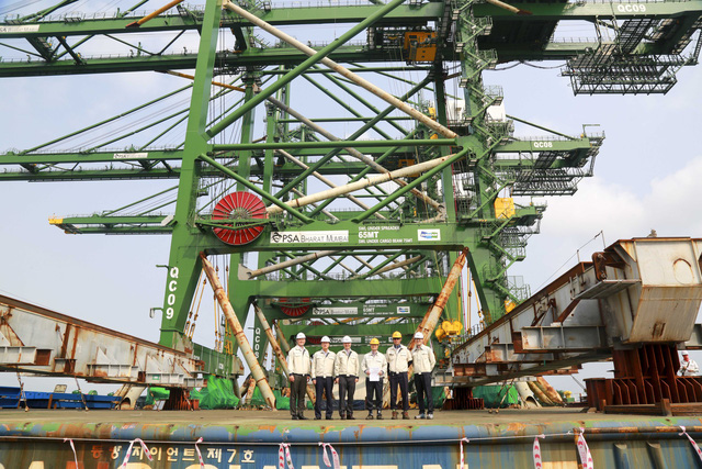 People stand beside three rail-mounted quay cranes produced by Doosan Heavy Industries in Vietnam, shipped to India in March 2018. Photo: Tuoi Tre