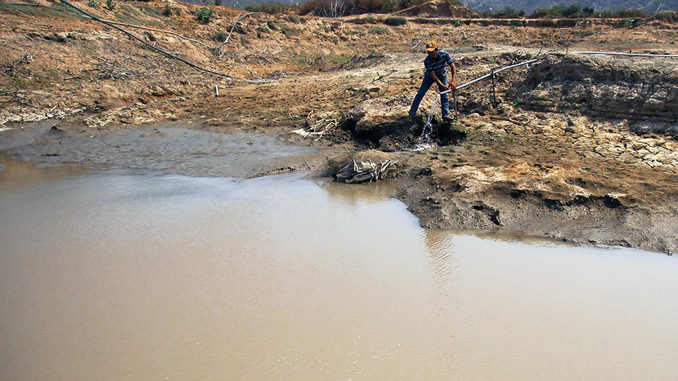 A farmer handles a pipe that channels water to his pond in Ninh Thuan Province, south-central Vietnam. Photo: Tuoi Tre