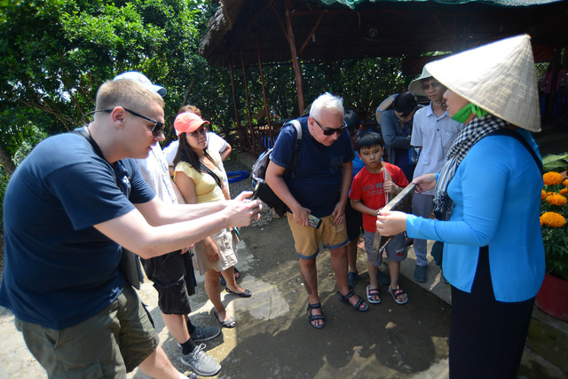 Foreign tourists watch as a guide demonstrates how honey is harvested in southern Vietnam. Photo: Tuoi Tre