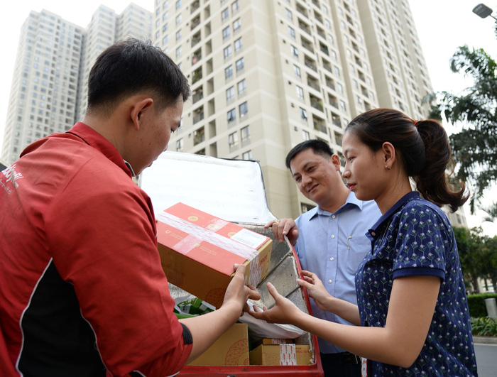 A deliveryman from Adayroi, an online retailer, hands a package to customers at a luxurious apartment building in District 2, Ho Chi Minh City, Vietnam. Photo: Tuoi Tre