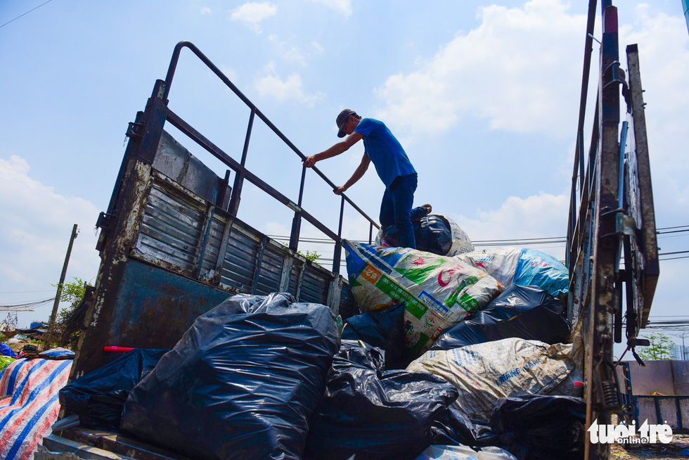 A man loads bags of scrap metal onto a truck.