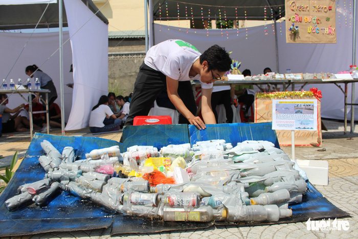 A student handles a bottle configuration of a sperm whale which died with the body filled with trash in Spain in February, at the Earth Day event in Da Nang, central Vietnam, on April 22, 2018.  Photo: Tuoi Tre