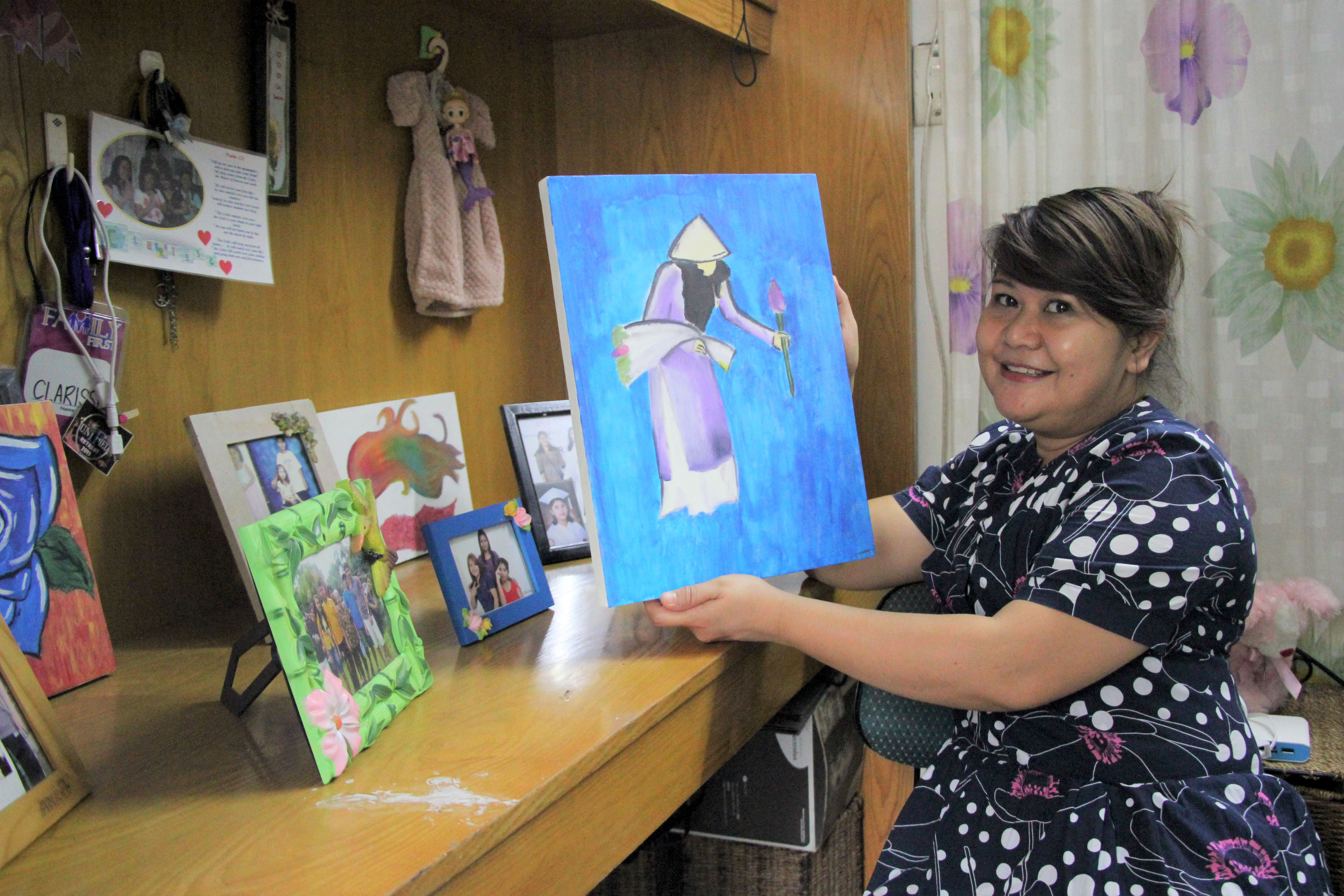 Clarisse Cantos shows a painting made by her daughter displayed her rented room in District 3. Photo: Tuoi Tre