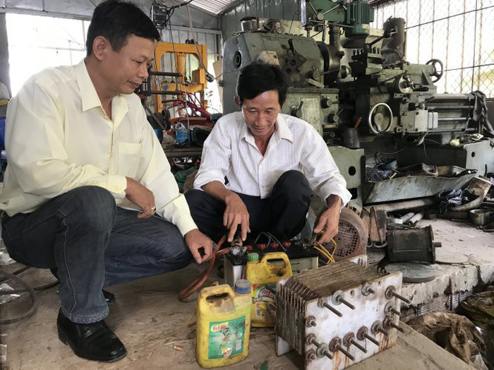 Nguyen Van Nung (white) talks about his rudimentary steam-powered machine. Photo: Tuoi Tre