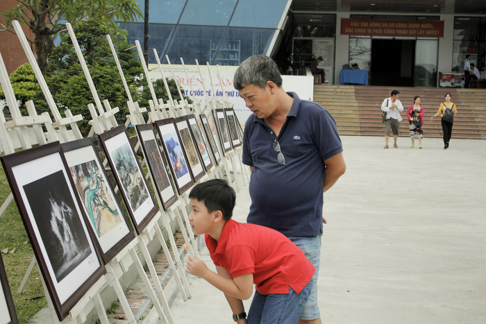 A man and his son watch photos displayed at the exhibition in Da Nang, central Vietnam. Photo: Tuoi Tre