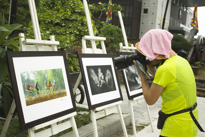 A woman takes a photo of an exhibited photo. Photo: Tuoi Tre