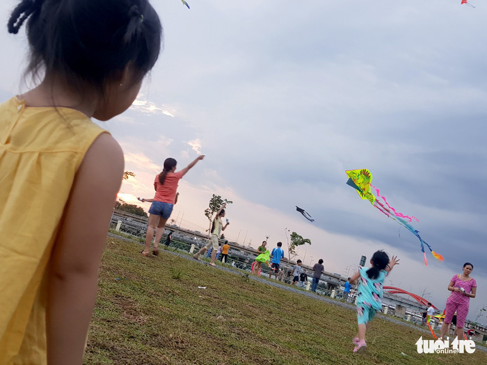A kid runs after the kite as her mom flies it. Photo: Tuoi Tre