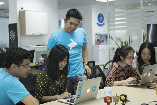 Kevin Tung Nguyen (standing) talks with colleagues at his company – Jobhop. Photo: Tuoi Tre