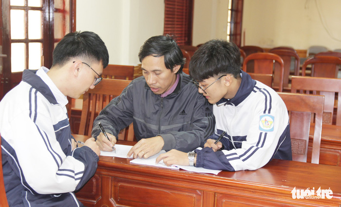Mai Nhat Anh (R) and Phung Van Long discuss with their teacher, Mai Van Quyen, about the project. Photo: Tuoi Tre