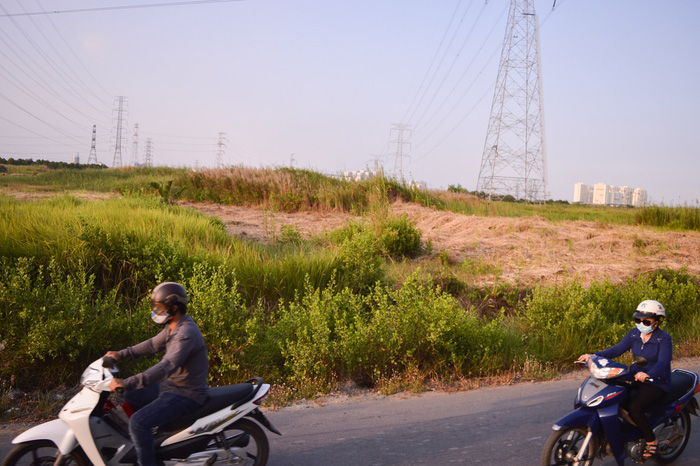 Motorcyclists zoom past a public plot of land in Phuoc Kien Commune, Nha Be District that was agreed to be sold at a cheap price to a private company in a June 2017 deal that never went through. Photo: Tuoi Tre