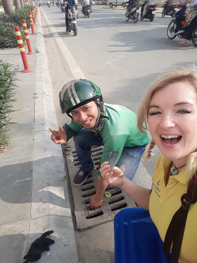 The GrabBike drivers are pictured trying to retrieve the bank card for Albany Owens from a drain in Hanoi in this photo posted on her Facebook on May 8, 2018.