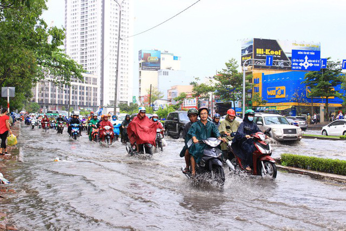 Commuters travel along inundated Nguyen Huu Canh Street. Photo: Tuoi Tre
