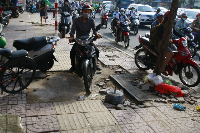 Motorbikes run on the sidewalk with tile loss of a street in Ho Chi Minh City, Vietnam. Photo: Tuoi Tre