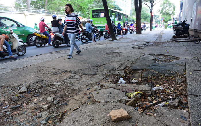 A girl walks on a damaged portion of the sidewalk along Hai Ba Trung Street in Ho Chi Minh City, Vietnam. Photo: Tuoi Tre