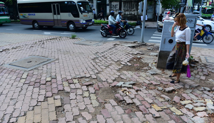 A woman goes on a damaged portion of the sidewalk of Nguyen Thi Minh Khai Street in Ho Chi Minh City, Vietnam. Photo: Tuoi Tre