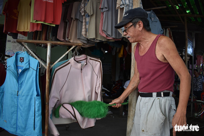 Nguyen Hoang Phuc removes dust from a shirt at his shop in the Chau Long Market in An Giang Province, southern Vietnam. Photo: Tuoi Tre