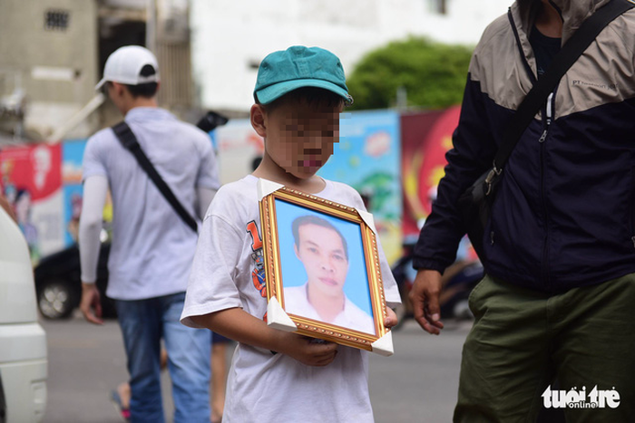 The son of Nguyen Van Thoi holds his portrait as the family takes his body to the south-central province of Binh Dinh for a funeral. Photo: Tuoi Tre