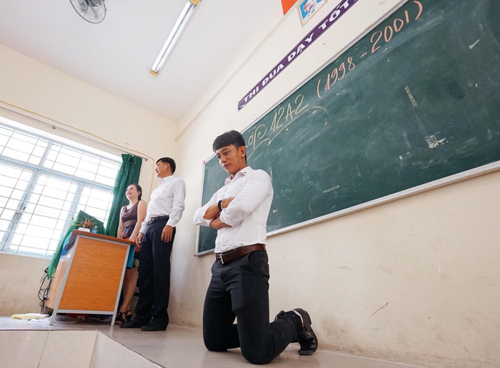 An alumnus recreates failing a verbal test and being forced to kneel by the teacher.