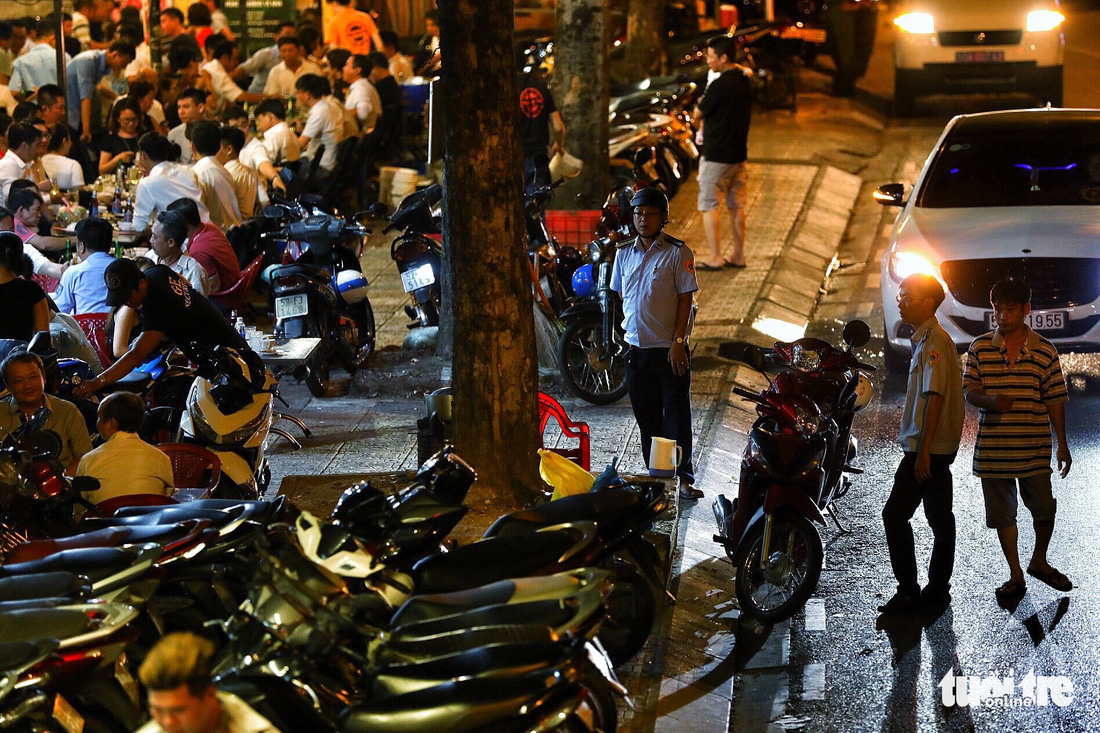 Sidewalk officials stand in front of a restaurant on Hoang Sa Street in District 1, Ho Chi Minh City, Vietnam, asking illegally parked motorcycles to move. Photo: Tuoi Tre