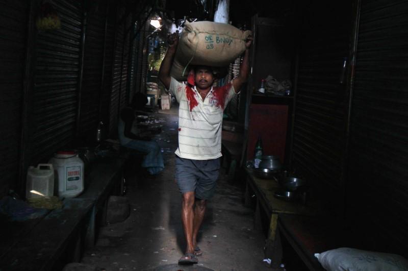 A labourer carries a sack filled with rice through an alley at a wholesale market in Kolkata March 14, 2014. Photo: Reuters