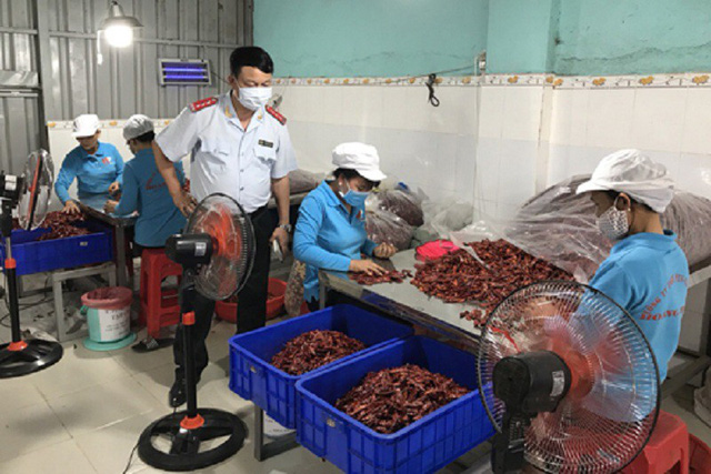 An inspector from the Ministry of Agriculture and Rural Development  observes the production process at a chili powder-making establishment . Photo: Tuoi Tre