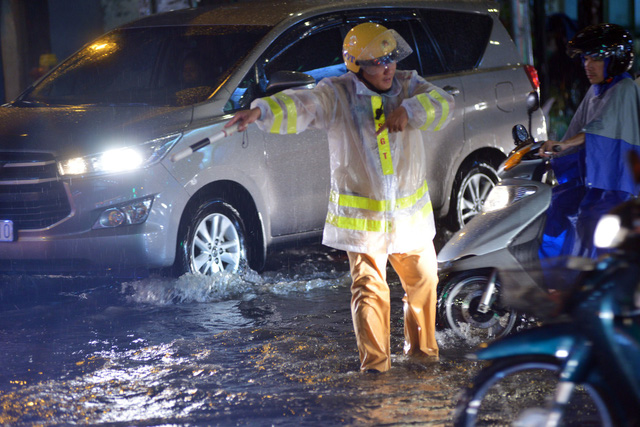 A traffic police officer works under the heavy rain in Binh Thanh District.